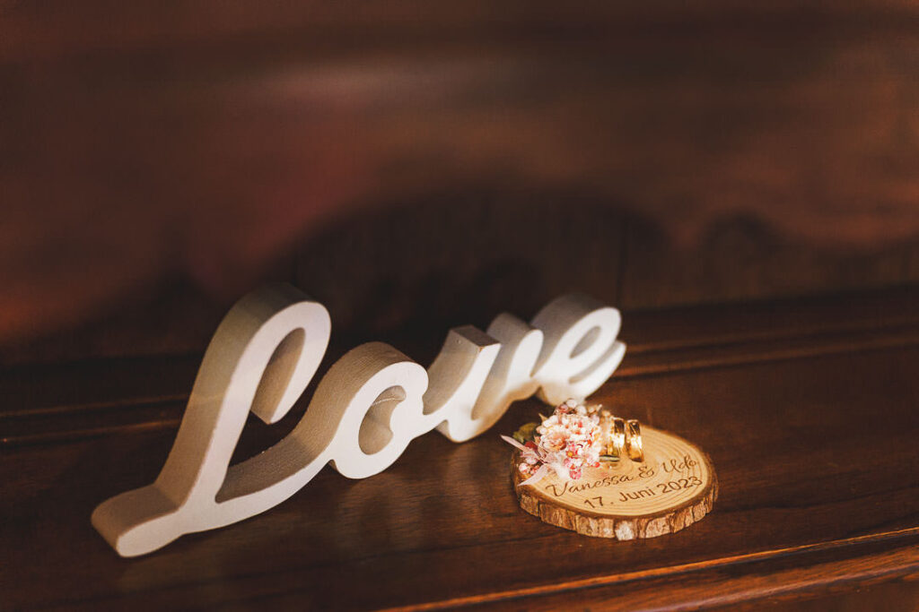 Ein Love Zeichen mit den Hochzeitsringen des Brautpaares dekorativ angeordnet